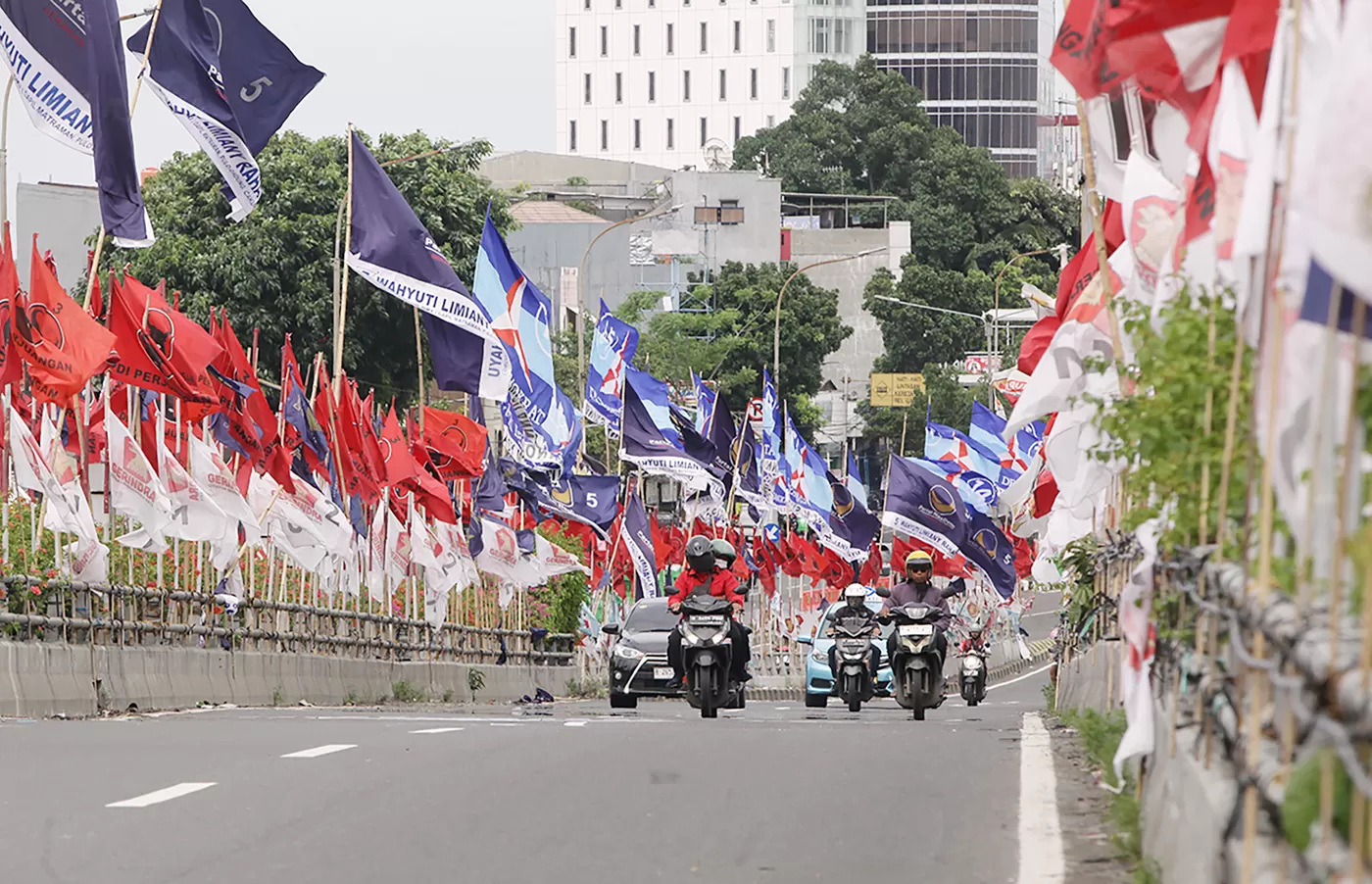 Deretan bendera partail politik membahayakan pengendara moto di fly over Matraman, Jakarta, Jumat (19/1/2024). (DERY RIDWANSAH/ JAWAPOS.COM)