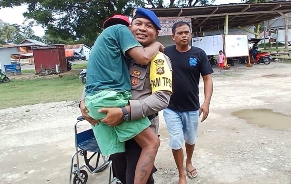 bertugas sebagai anggota Pengamanan TPS di Desa Yosonegoro Kecamatan Limboto Barat Kabupaten Gorontalo membantu salah satu warga Disabilitas.(Fhms-pol)