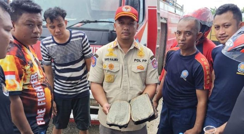 Plt Kepala Bidang Damkar Linmas Satpol PP Damkar Pohuwato, Bayu Eka Septian Kaluku saat Temukan Alquran di puing-puing Kantor PDAM yang Terbakar.(foto/Ist)