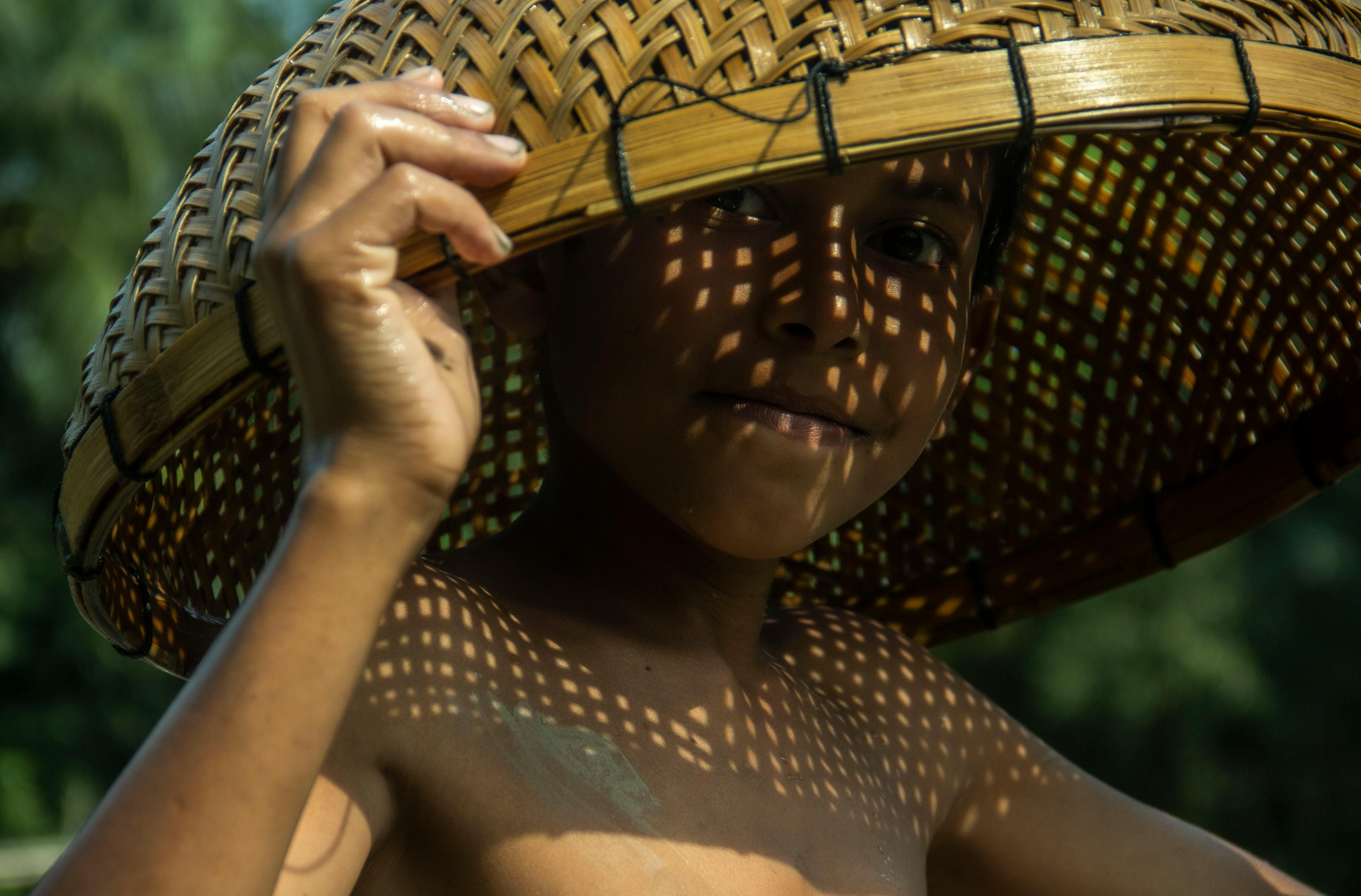anak kecil menggunakan topi anyaman bambu