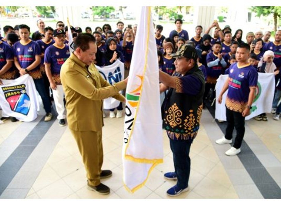Gubernur Gusnar Ismail menyerahkan pataka kepada Ketua Umum Kormi Provinsi   Gorontalo Mikson Yapanto pada pelepasan kotingen Fornas VIII di rumah jabatan gubernur. (Foto : Haris)