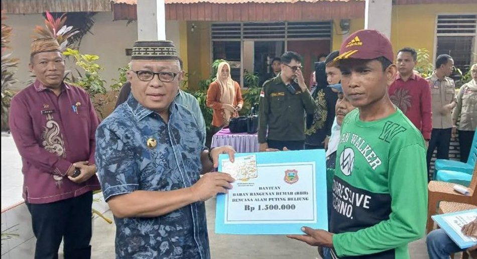 Bupati Gorontalo, Sofyan Puhi saat  menyalurkan bantuan senilai Rp650 juta  bagi 96 Kepala Keluarga (KK) korban bencana angin puting.(F:humas)