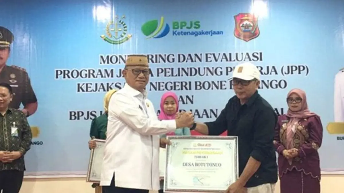 Bupati Bone Bolango, Ismet Mile saat menyerahkan piagam penghargaan Terbaik I dalam capaian jumlah pendaftar kepesertaan BPJS Ketenagakerjaan terbanyak melalui JPP.(F.Indra-Kominfo).