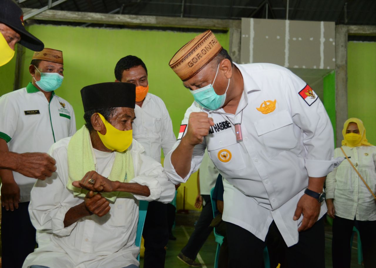 PEDULI: Gubernur Gorontalo Rusli Habibie saat melakukan salam “corona” dengan salah satu masyarakat penerima bantuan pangan bersubsidi di Kecamatan Asparaga Kabupaten Gorontalo,  Selasa (25/11/2020). (Salman)