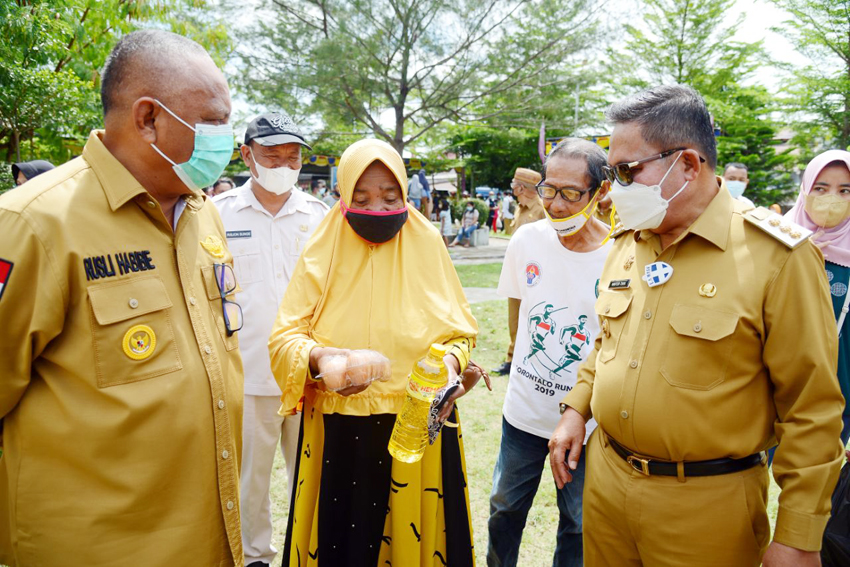 Gubernur Gorontalo Rusli Habibie bersama Wali Kota Gorontalo Marten Taha saat menyapa salah seorang masyarakat yang membeli di pasar murah yang kembali dilaksanakan oleh Pemprov Gorontalo khusus untuk maysarakat di Kota Tengah, Kota Gorontalo, Senin (10/5