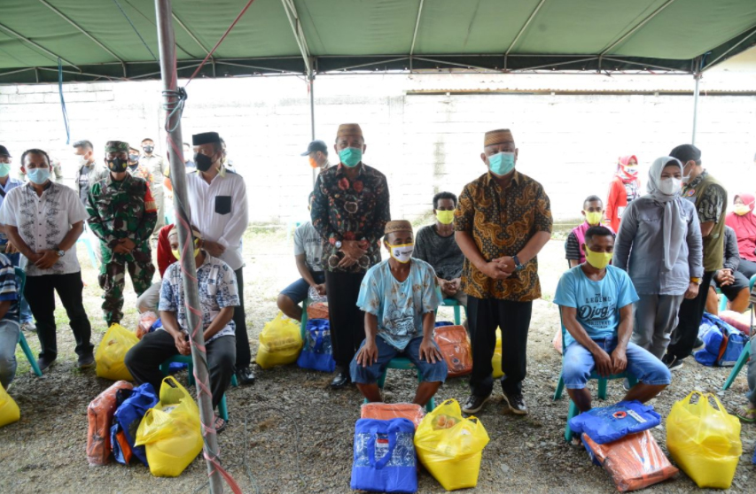 Gubernur Gorontalo Rusli Habibie (batik coklat) didampingi istri saat menyerahkan bantuan kepada korban kebakaran di lokasi Barak Mutiara Dusun Mootilango, Desa Diloato, Kecamatan Paguyaman, Kabupaten Boalemo, Jumat (9/7/2021). Foto: Salman/humas