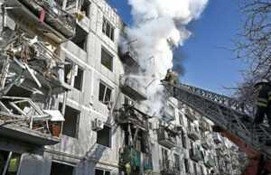 Pemadam kebakaran berusaha memadamkam api di sebuah gedung yang terbakar setelah terkenab bom di Chuhuiv, Ukraina Timur, seiring upaya invasi Rusia kemarin (24/2). (AFP)