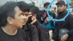 Pria pertama pemukul Ade Armando memakai topi hitam (tangkapan layar)