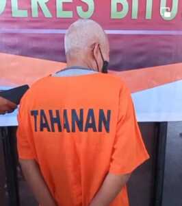Penampakan tersangka yang sudah beruban itu mengenakan rompi oranye bertuliskan tahanan.