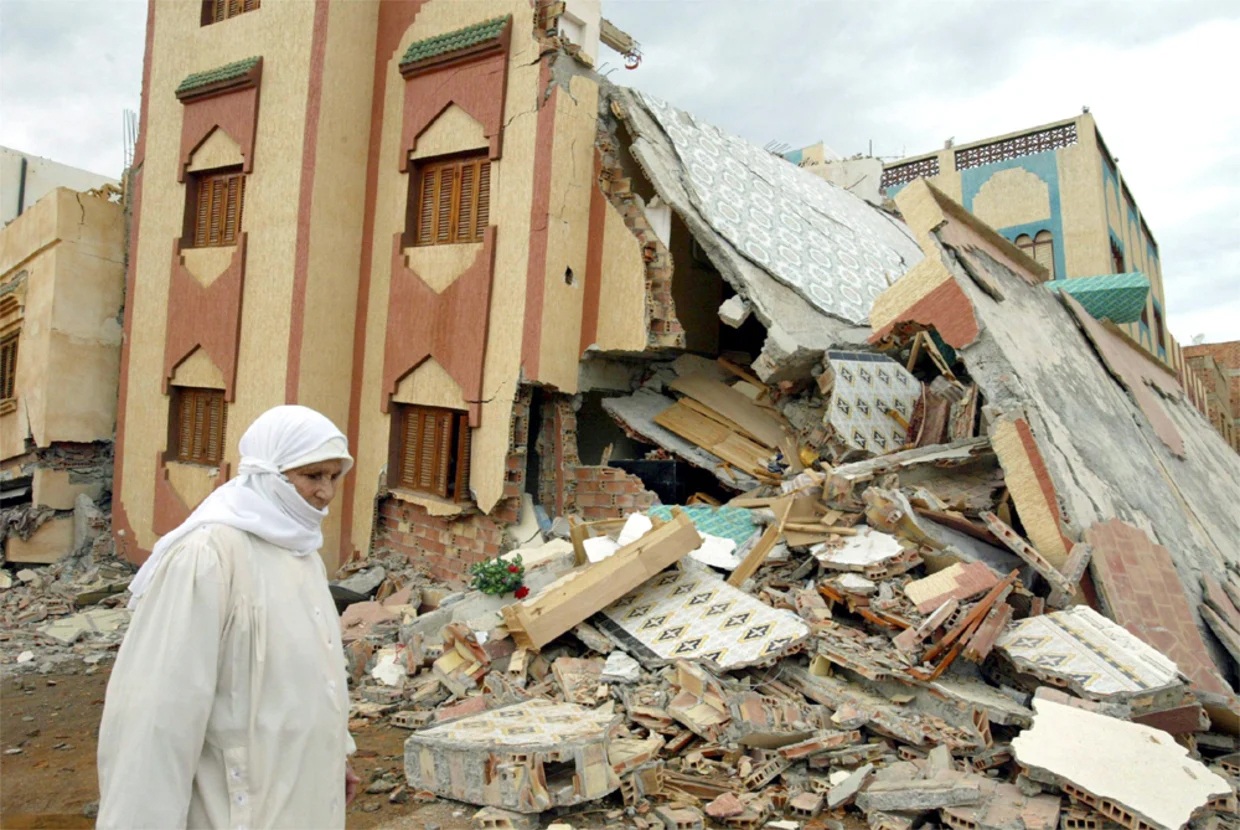 PORAK-PORANDA: Seorang ibu melintas di depan sebuah bangunan yang ambruk akibat dilanda gempa di Marrakesh.