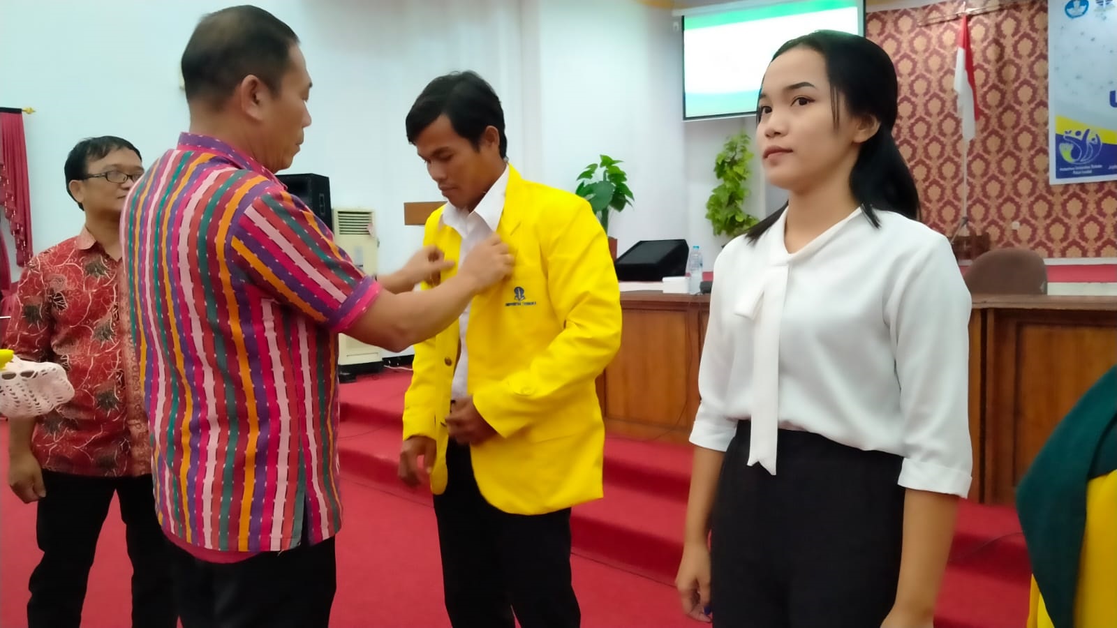 SIMBOLIS: Sekda Landak Vinsensius menyematkan baju almamater kepada dua orang perwakilan mahasiswa pokjar Landak di Aula Kantor Bupati Landak, Sabtu (9/9).