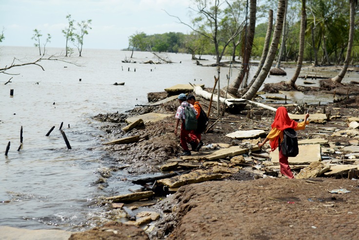 Sejumlah anak-anak berjalan melintasi jalan umum yang rusak akibat abrasi air laut di Desa Kuala Karang, Kecamatan Teluk Pakadai, Kabupaten Kubu Raya, Kamis (7/9).