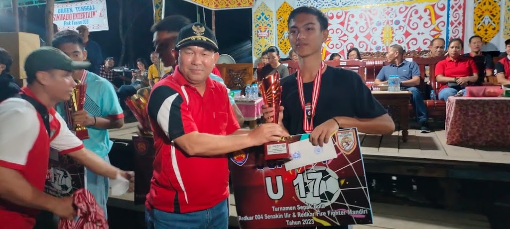 PENYERAHAN HADIAH: Pj Bupati Landak Samuel menyerahkan hadiah kepada pemenang turnamen olahraga Relawan Kebakaran 004 dan Barisan Pemadam Kebakaran di Lapangan Sepak Bola Pak Tosam Dusun Senakin.