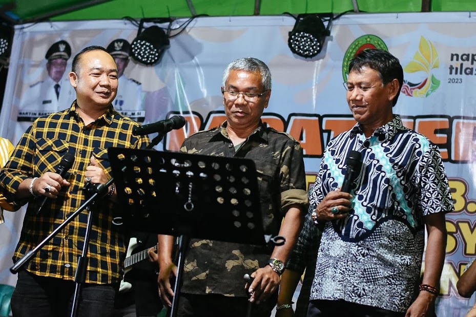 TIGA SERANGKAI: Bupati Martin Rantan, Wakil Bupati Farhan, dan Sekda Alexander Wilyo menyanyikan lagu Kemabok Tuak dan Ikan di dalam Kolam pada di Lapangan Sepakbola Parit Berdiri, Desa Pelang. IST