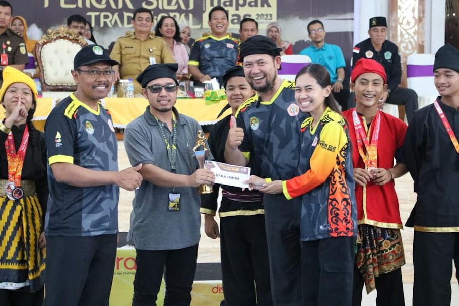 JUARA UMUM: Ketua Panitia, Maria Raissa Sofia Rantan, menyerahkan trofi serta hadiah kepada Perguruan Silat PSHT yang berhasil menjadi juara umum pada Festival Pencak Silat Tradisional, Senin (23/10).