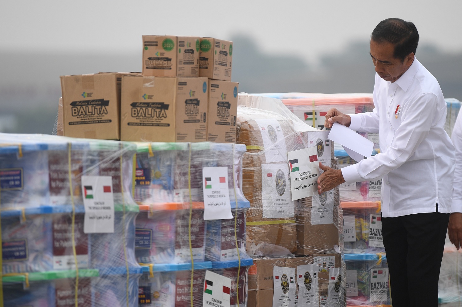 Presiden Joko Widodo menempelkan stiker pada barang bantuan untuk Palestina di Pangkalan Udara TNI AU Halim Perdana Kusuma, Jakarta, Sabtu (4/11/2023). Presiden melepas bantuan tahap pertama yang akan diterbangkan dengan tiga pesawat berisi 51,5 ton bantu