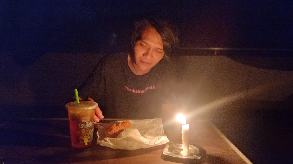 DITERANGI LILIN: Seorang warga Sukadana, menikmati makan malamnya dengan hanya diterangi lili lantaran kondisi listrik sedang padam, Selasa (28/11) malam lalu.
