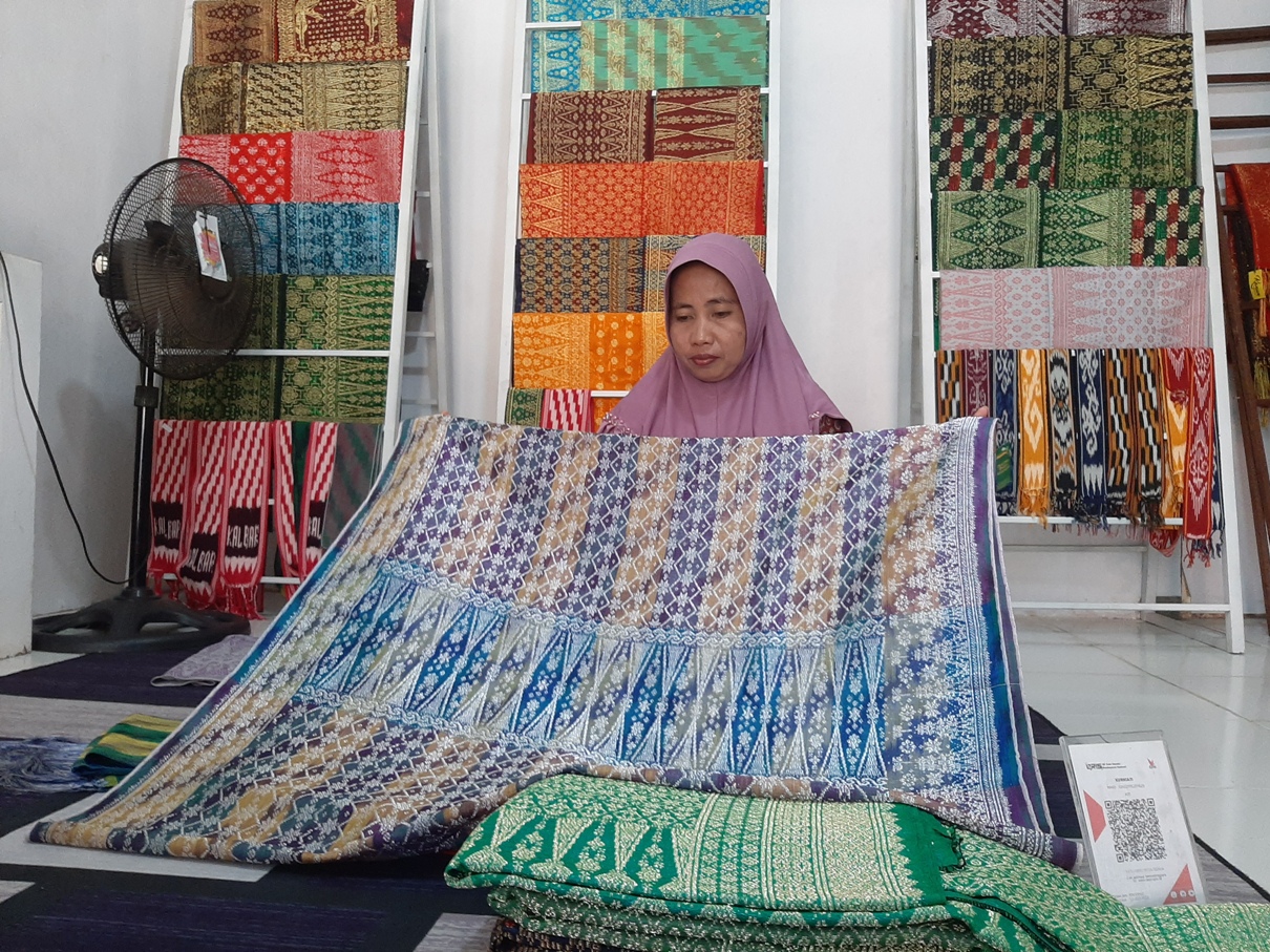 Kurniati sedang merapikan kain-kain songketnya. Setelah dua tahun sepi pembeli, penjualan kain songketnya pun kembali meroket usai pandemi.