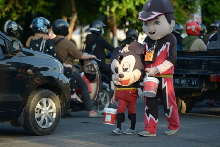 BADUT: Seorang badut dewasa bersama badut ana-anak berjalan menyusuri ruas jalan di Kota Pontianak, beberapa waktu lalu.