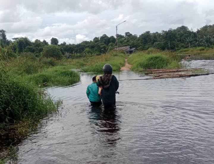 BANJIR: Warga berjalan kaki melewati banjir yang memutus akses jalan darat di Dusun Telayar.