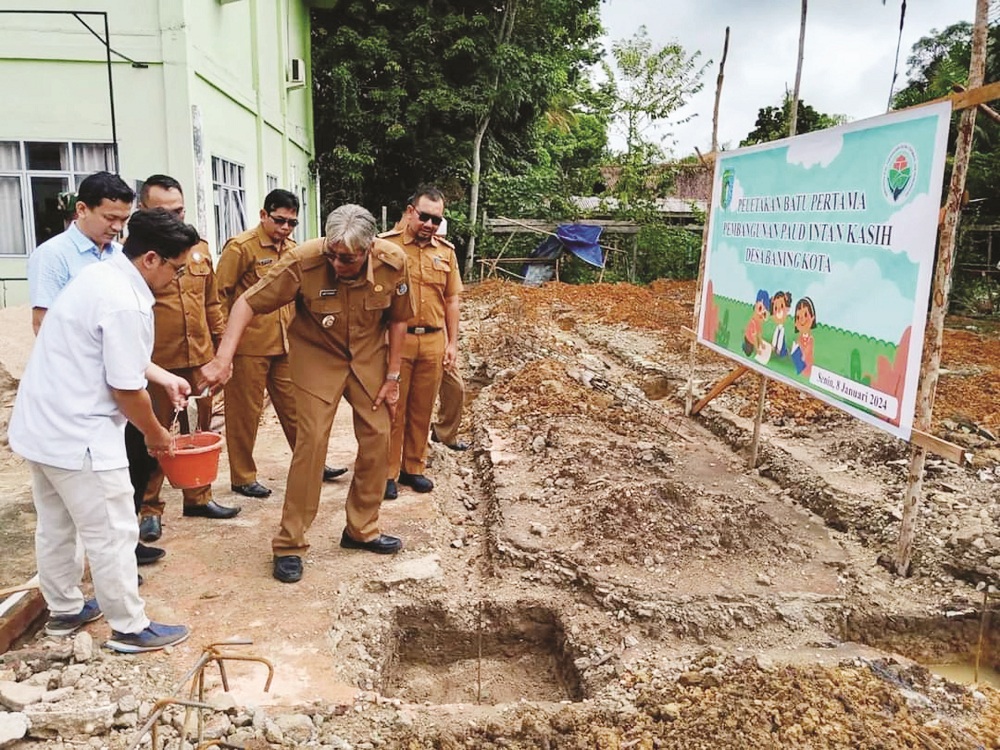 PELETAKAN BATU : Bupati Sintang saat meletakkan batu pertama pembangunan PAUD Intan Kasih Desa Baning Kota, di Kantor Desa Baning Kota.