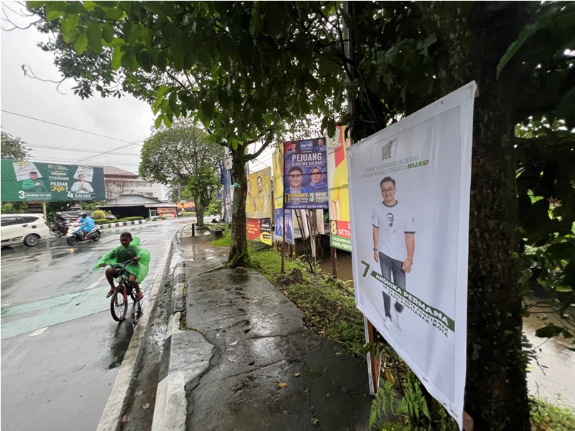 Seorang bocah melintas di depan Alat Peraga Kampanye (APK) pemilu di simpang Jalan Jenderal Urip, Jumat (12/1). Pemasangan APK di tempat terlarang seperti pepohonan, trotoar, dan tiang listrik.