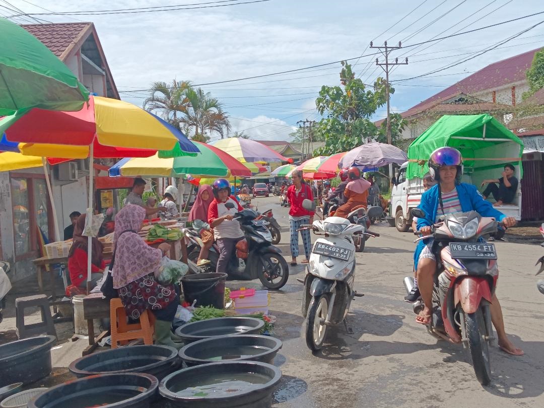 PINGGIR JALAN: Pedagang di Pasar Pagi Putussibau tampak berjualan di pinggir Jalan Diponegoro karena kondisi pasar saat ini masih tergenang.