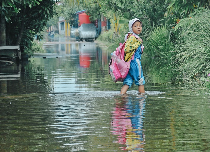 7.	AIR ROB: Seorang anak pulang sekolah bertelanjang kaki saat air pasang di Desa Sungai Renggas, Kubu Raya.