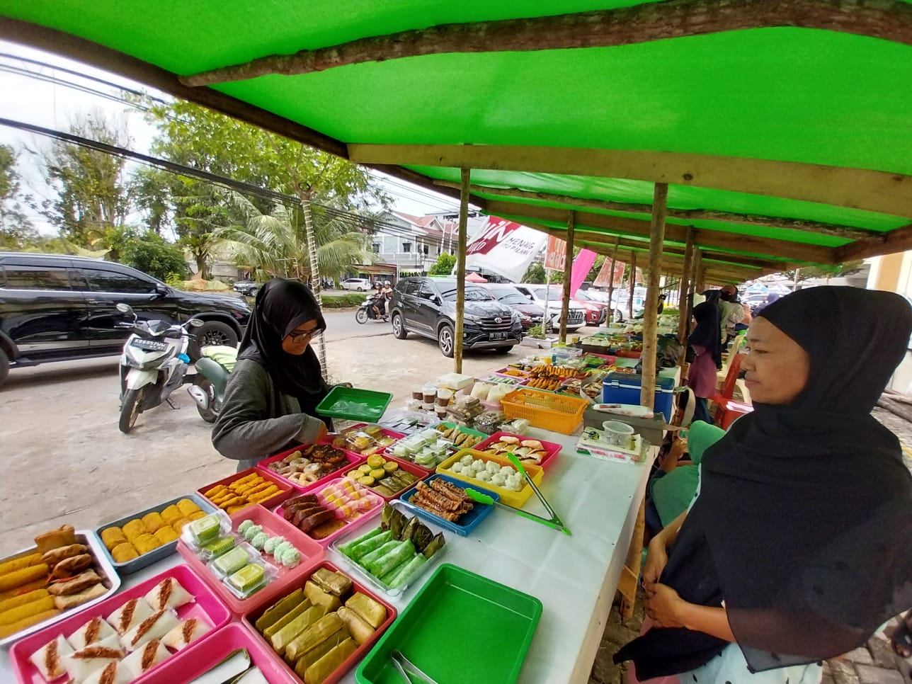 Sri Dewi, penjual takjil di halaman Masjid Darunnajah, saat melayani pembeli. IST