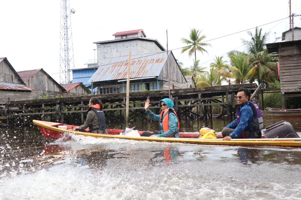 Pj Ketua TP-PKK Kalbar Windy Prihastari menaiki perahu motor menyusuri sungai saat melaksanakan berbagai kegiatan sosial di Desa Sepuk Laut, Kabupaten Kubu Raya, Kamis (28/3).