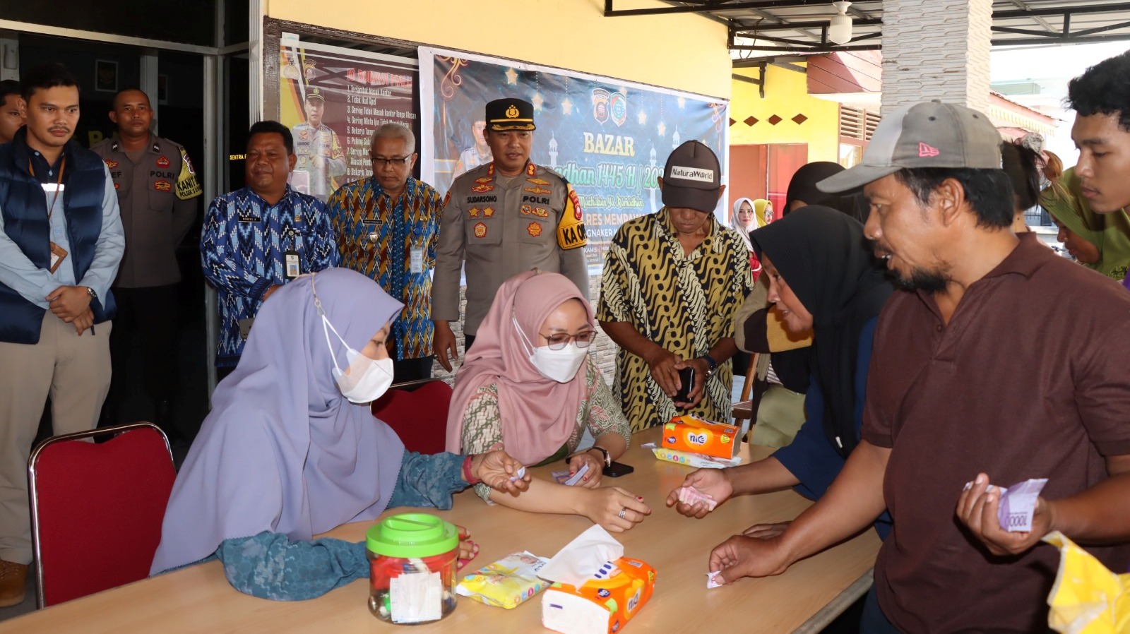 MELAYANI: Petugas melayani masyarakat yng membeli paket sembako murah di Mapolsek Sungai Kunyit.