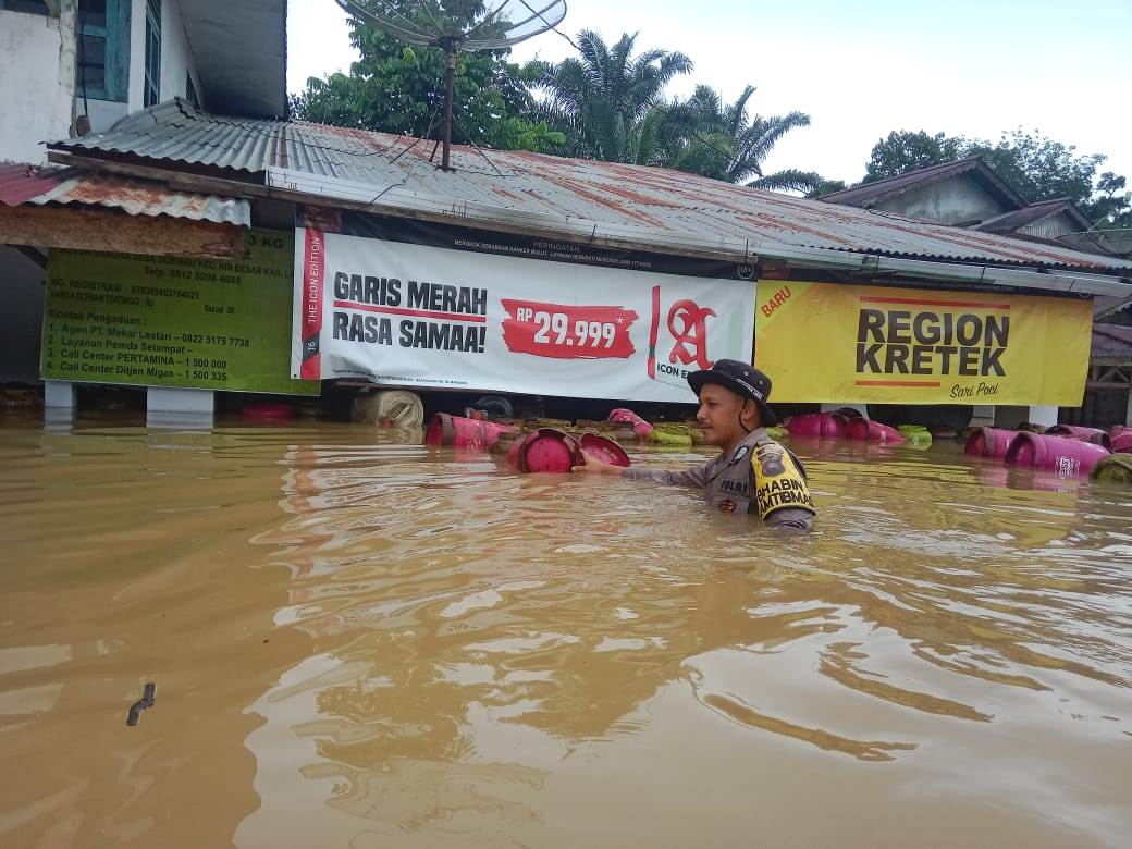 Polisi saat menyelamatkan warga dan barang pada bencana banjir di Desa Serimbu, Kecamatan Air Besar Kamis (23/5).