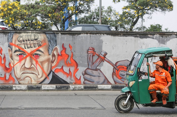 Pengendara melintas didepan mural wajah Perdana Menteri Israel Benjamin Netanyahu di Jakarta, Jumat (31/5/2024). Komunitas Berkemas membuat mural tersebut sebagai bentuk solidaritas dan dukungan kepada warga Palestina atas serangan pasukan Israel ke kota