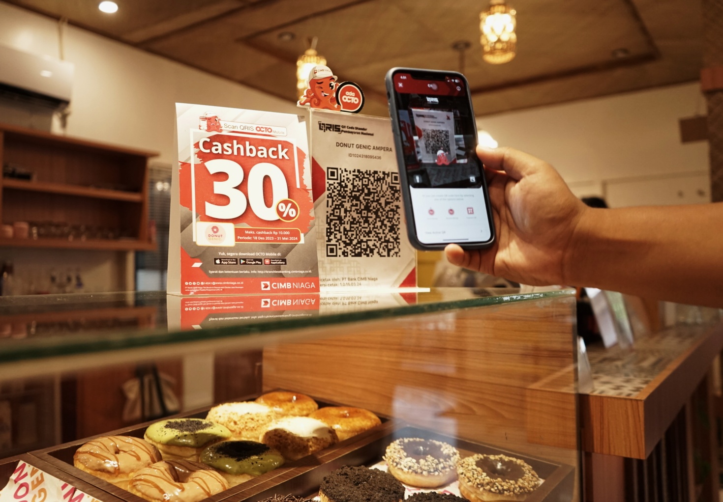 TRANSAKSI: Seorang konsumen tengan membayar donat pesanannya di Kafe Donutsgenic Pontianak, Jl Ampera Pontianak dengan metode QRIS via aplikasi OCTO Mobile CIMB Niaga.