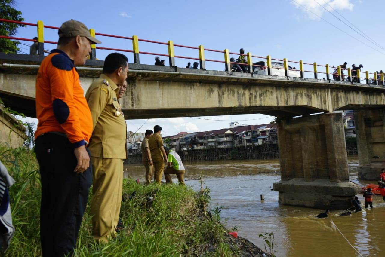 GOTONG ROYONG: Pj Bupati Landak Gutmen Nainggolan memantau pembersihan sampah kayu di jembatan lama Ngabang, Selasa (11/6).