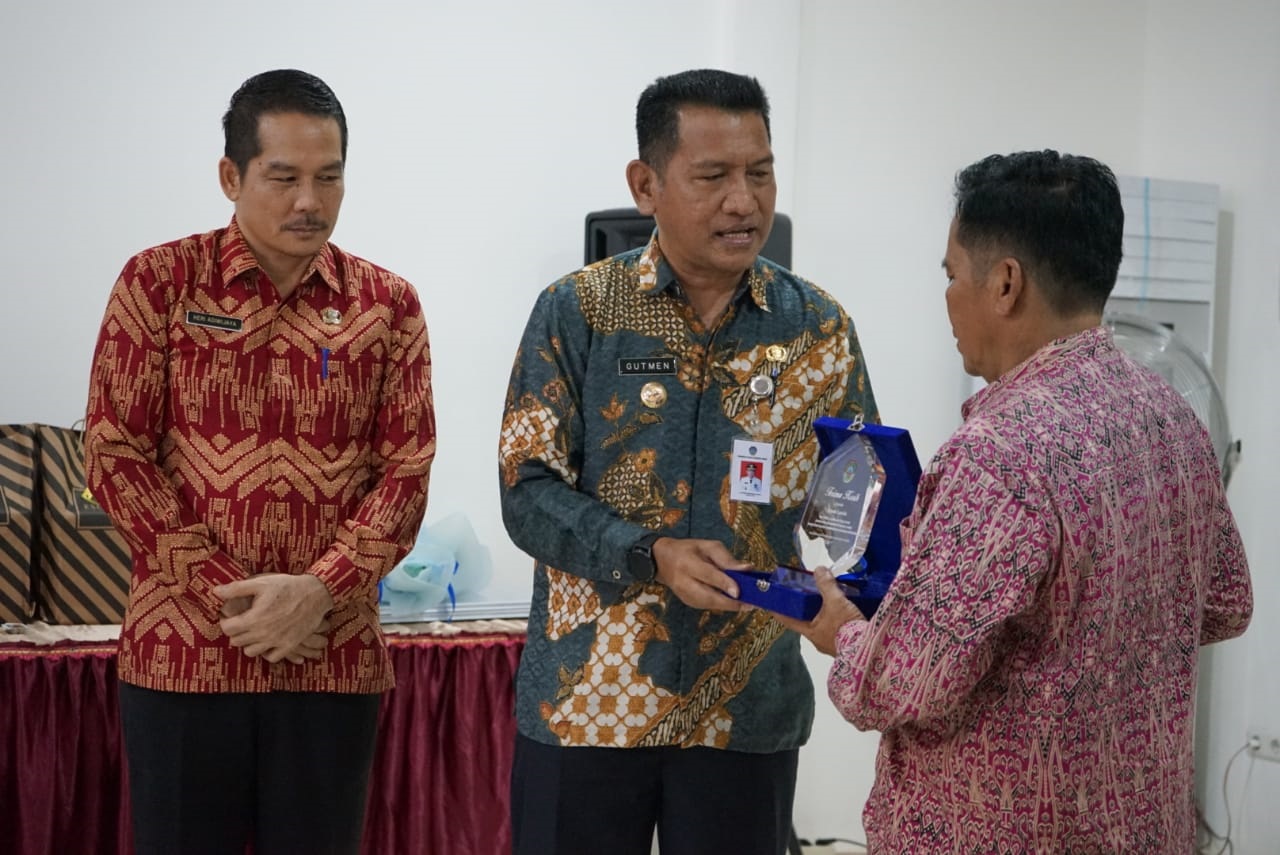 PENGHARGAAN: Pj Bupati Landak Gutmen Nainggolan menyerahkan plakat kepada dua ASN purna tugas Inspektorat Kabuapaten Landak, Kamis (4/7).