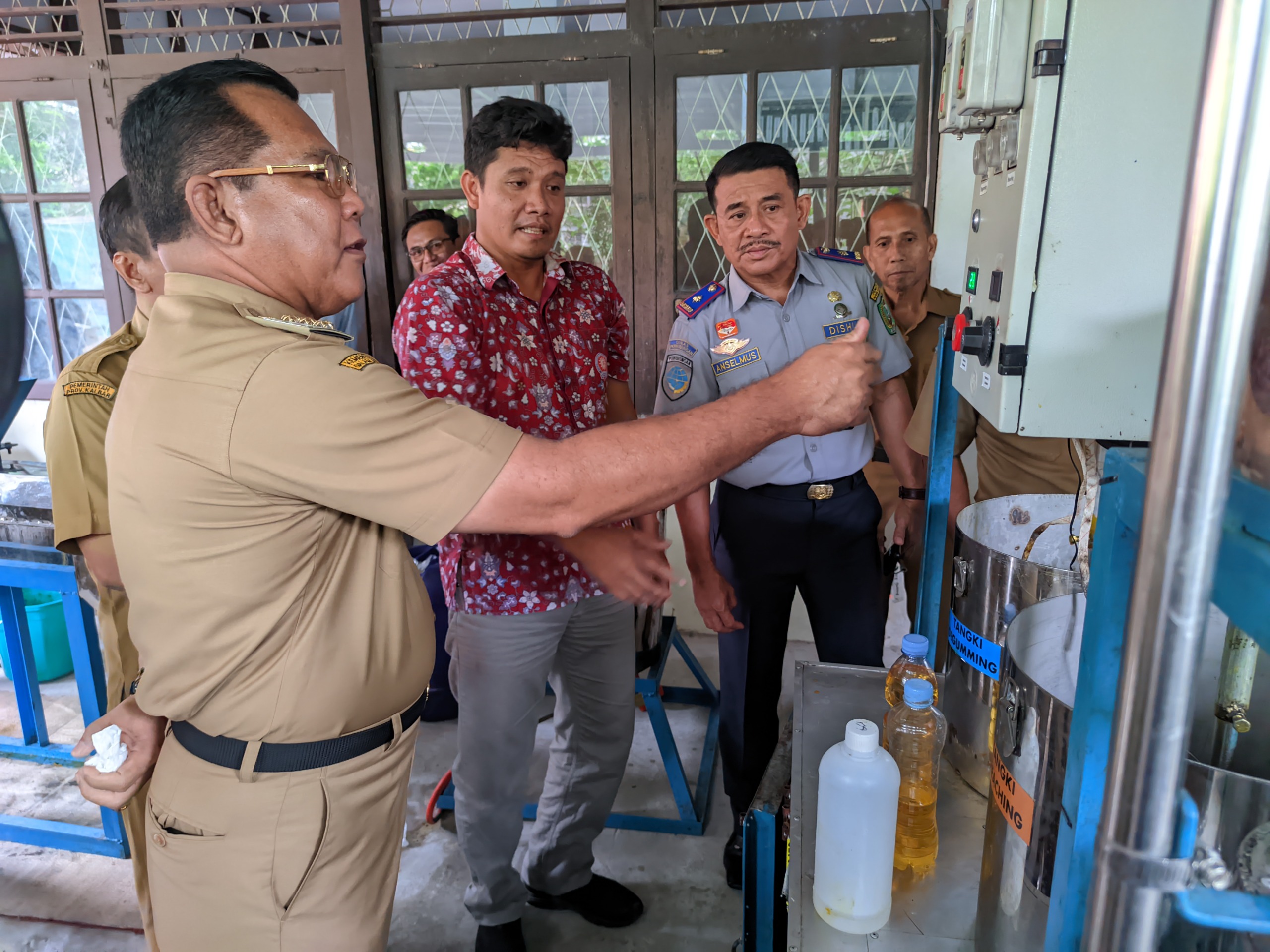Pj Bupati Sanggau saat melakukan uji coba mesin pengolah minyak sawit.