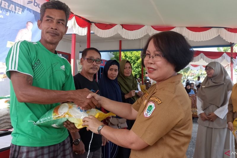 PANGAN MURAH: Asisten Bidang Perekonomian dan Pembangunan Setda Kapuas Hulu Triwati menyerahkan beras kepada salah satu warga saat gerakan pangan murah, Senin (29/7).