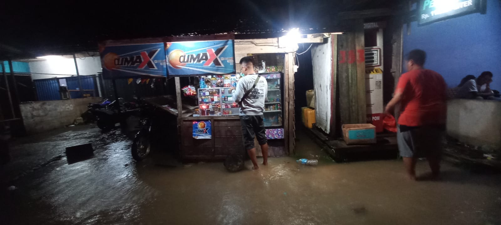 TERGENANG AIR: Seorang warga berada di kios milik warga, tidak jauh dari halaman rumah yang ikut tergenang, di Jalan Bhayangkara, Sukadana. DANANG PRASETYO/ PONTIANAK POST.