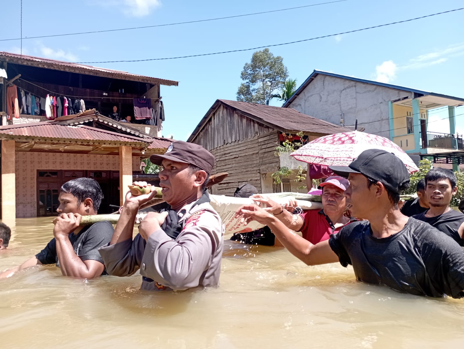 Anggota Kepolisian Sektor Menyuke bersama warga saat mengevakuasi warga yang sakit menggunakan tandu menuju rumah sakit.