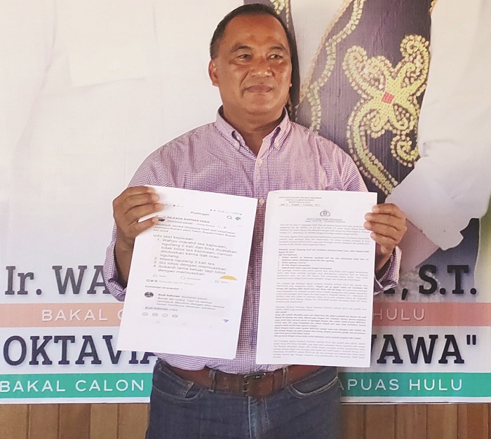 LAPORAN : M. Dahar Tim Bidang Hukum pasangan Wahyu-Wawa saat menunjukkan laporan mereka ke polisi.
