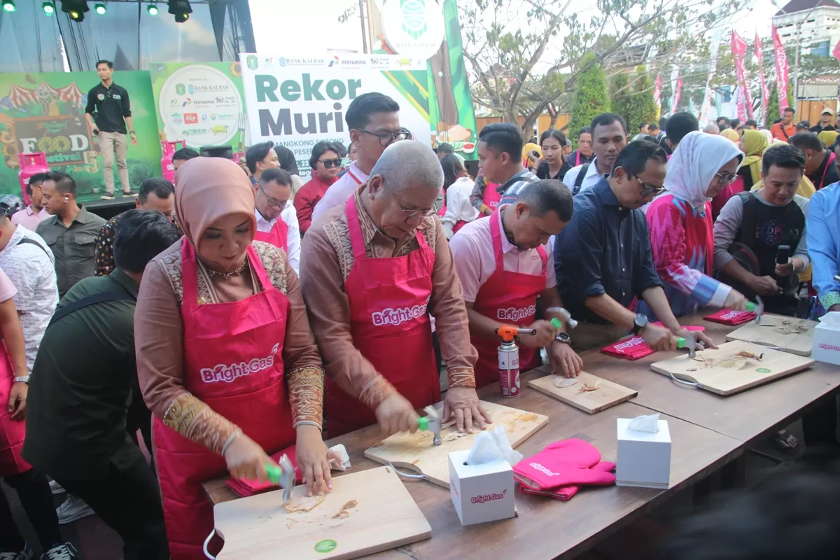 REKOR MURI: Pj Gubernur Kalbar Harisson dan Pj Ketua TP PKK Kalbar, Windy Prihastari saat ikut memecahkan rekor Muri memukul sotong kering dalam gelaran Kalbar Food Festival 2024.