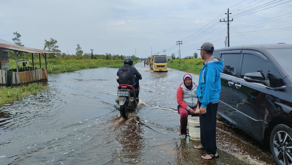 BANJIR: Warga membantu mengatur lalu lintas di titik Jalan Desa Galang yang terendam banjir.