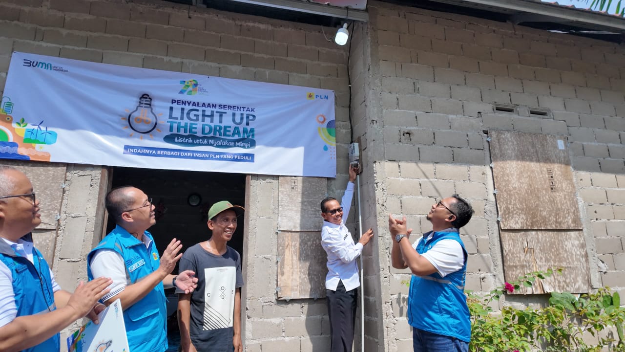 Simbolis penyalaan listrik Program Light Up The Dream oleh Kepala Desa Rasau Jaya Tiga, Tukiman (kedua dari kanan),  Senior Manager Niaga dan Manajemen Pelanggan, Albert Safaria (kedua dari kiri).