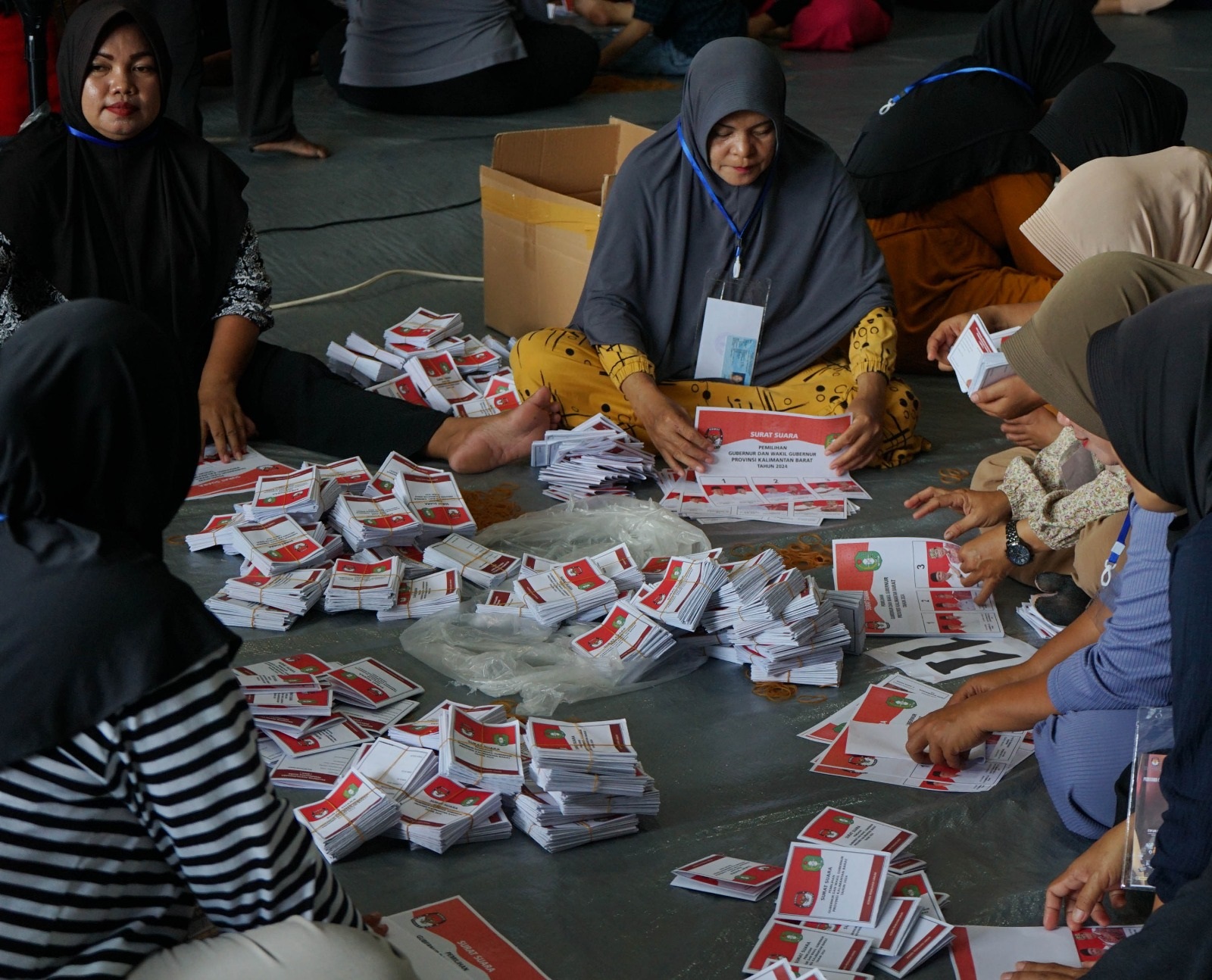 PELIPATAN KERTAS SUARA: Para ibu-ibu rumah tangga tampak ikut membantu proses pelipatan surat suara untuk pelaksanaan Pilkada Kubu Raya tahun 2024, Rabu (30/10).