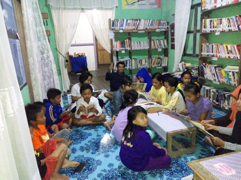 Jepriadi bersama anak-anak Dusun Semayong yang sedang menikmati buku di Rumah Baca Semayong. Pada masa-masa awal, rumah baca ini menempati ruang tamu di rumah orang tua Jepriadi di Dusun Semayong.