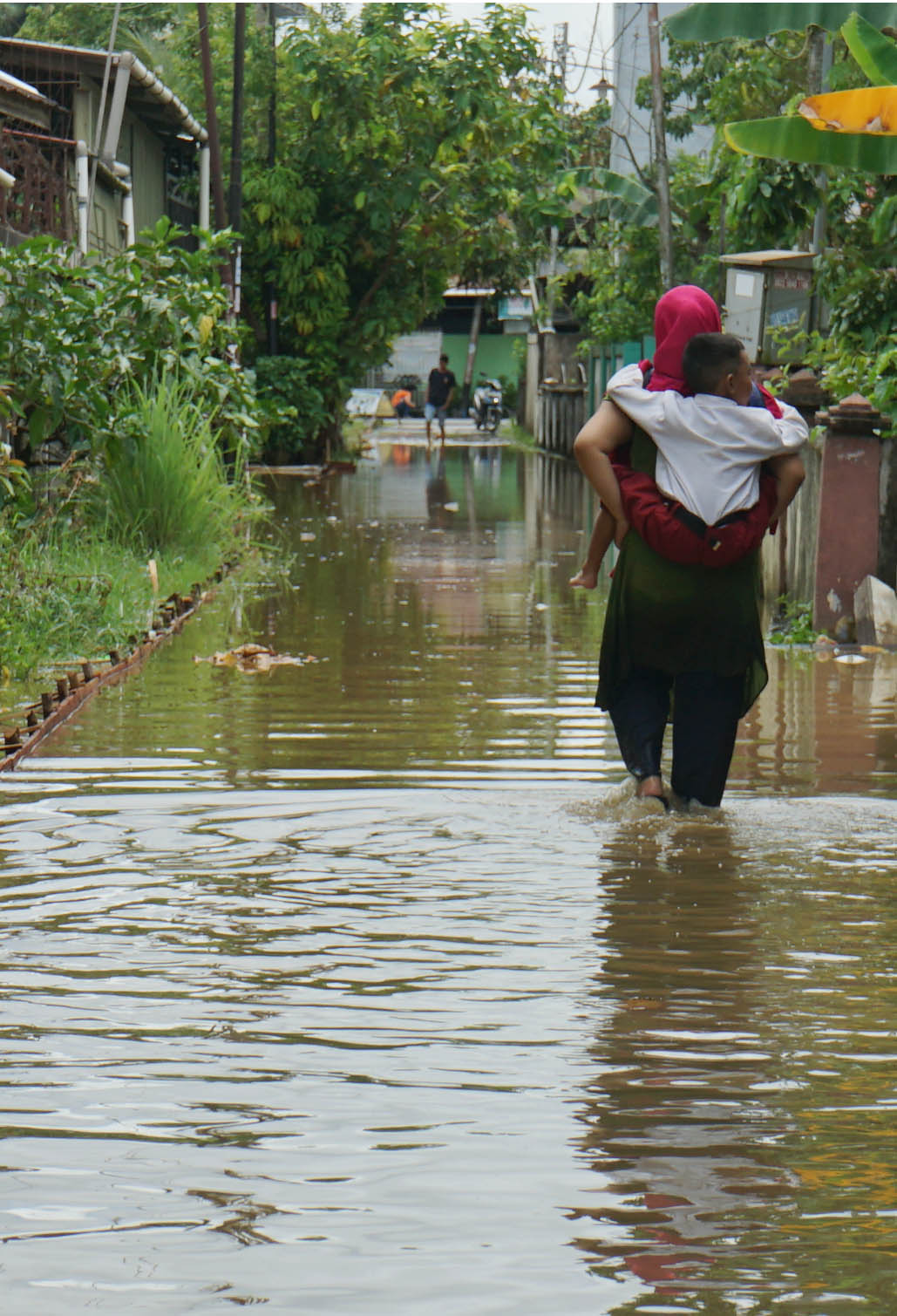 GENDONG ANAK: Seorang ibu menggendong anaknya melewati banjir rob di Gang Hijrah, Jalan Parit Haji Husin 1. Sejumlah kawasan rendah di Kota Pontianak terendam air akibat tingginya pasang air laut.