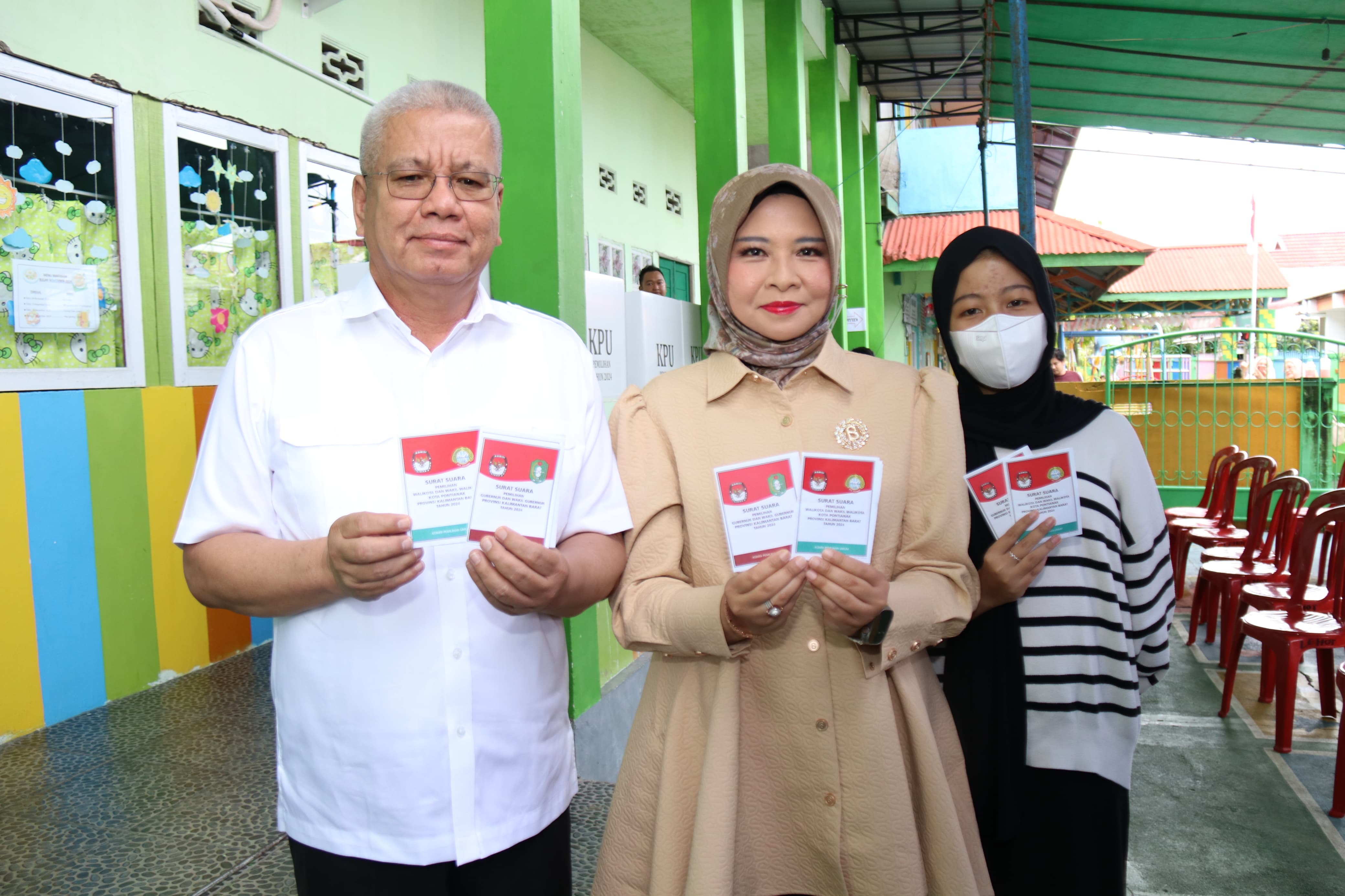 NYOBLOS : Pj Gubernur Kalbar Harisson bersama Pj Ketua TP-PKK Kalbar Windy menunjukkan surat suara sebelum nyoblos di TPS 54, Gang Sama Rukun, Kelurahan Sungai Bangkong, Kota Pontianak, Rabu (27/11).