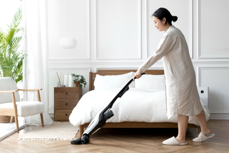 Ilustrasi membersihkan kamar menggunakan vacuum cleaner untuk menghilangkan tungau debu.