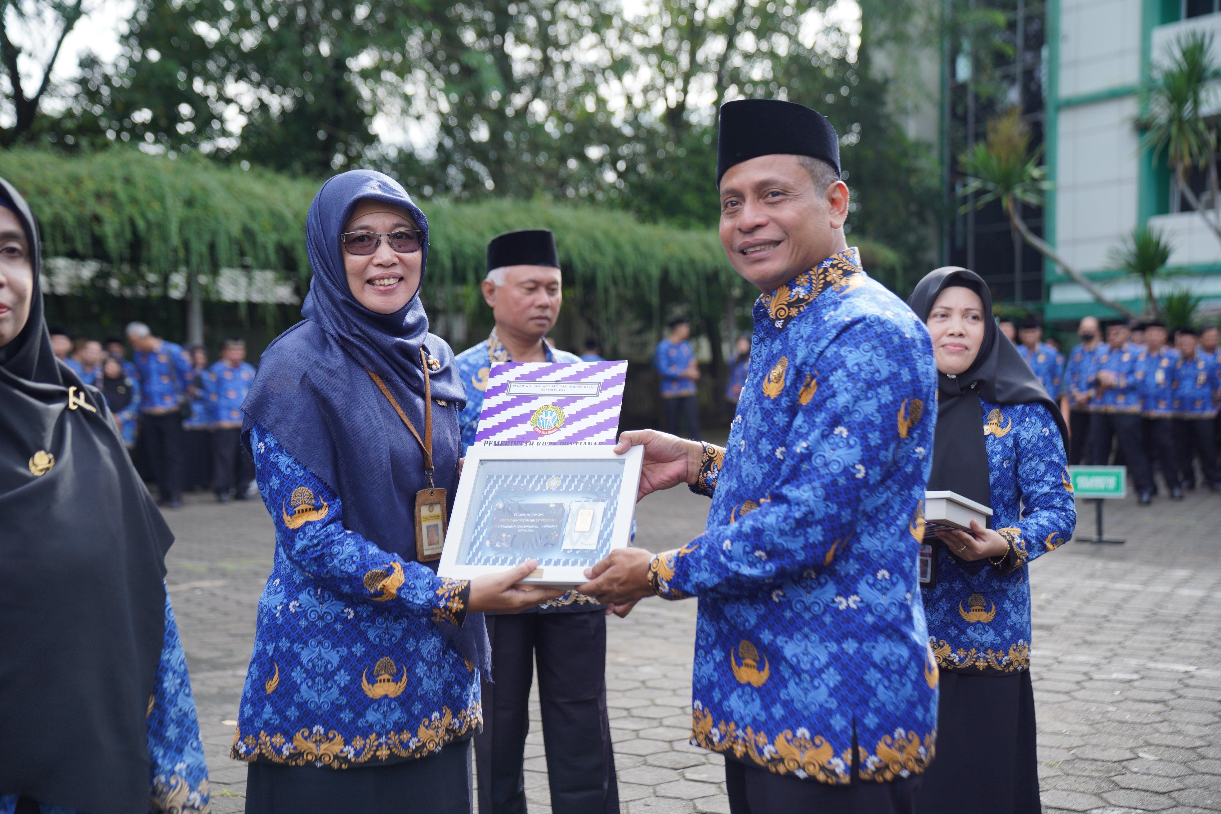 PERTAMA: Pj Wali Kota Edi Suryanto menyerahkan penghargaan kepada PNS berprestasi peringkat pertama.